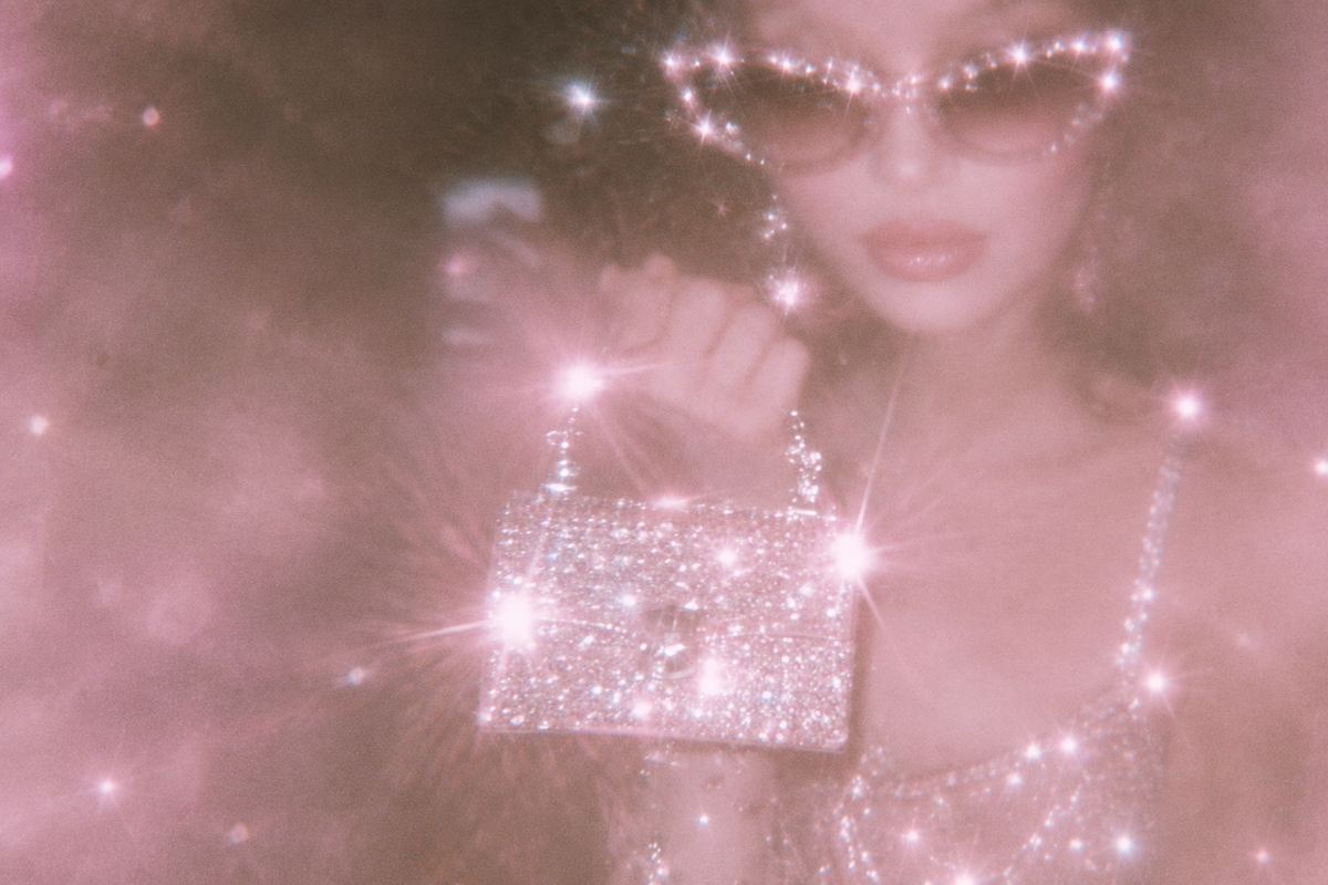Dreamy pink portrait of a woman wearing jeweled sunglasses and holding a sparkling rhinestone handbag.