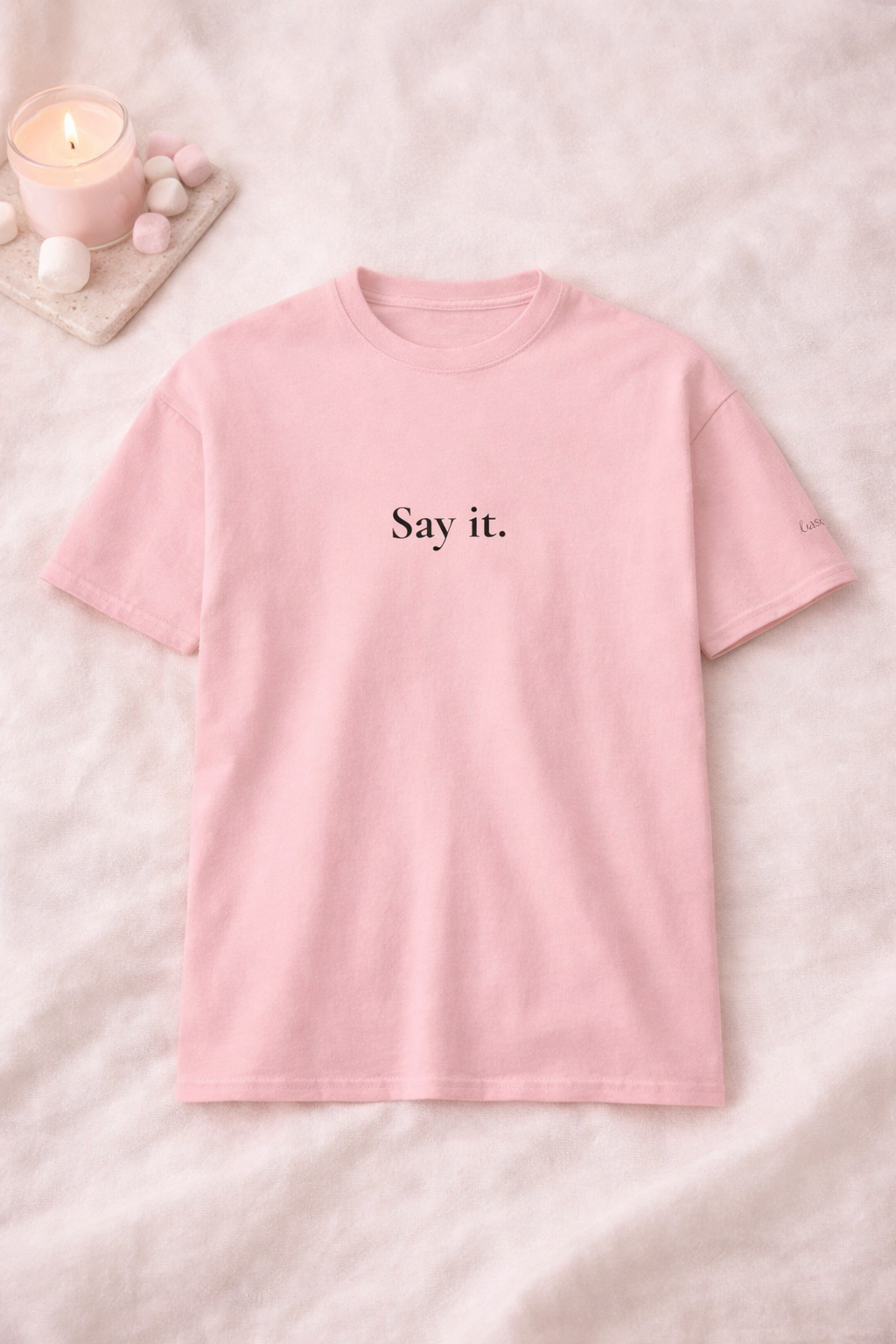 Pink t-shirt with 'Say it.' text on a soft pink background